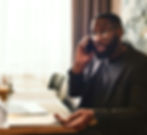 A marketer in a suit takes a phone call, with papers and laptop in front of him.