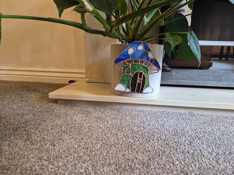 Thumbnail: Stained glass mushroom fairy door plant pot hanger decorating a large indoor plant