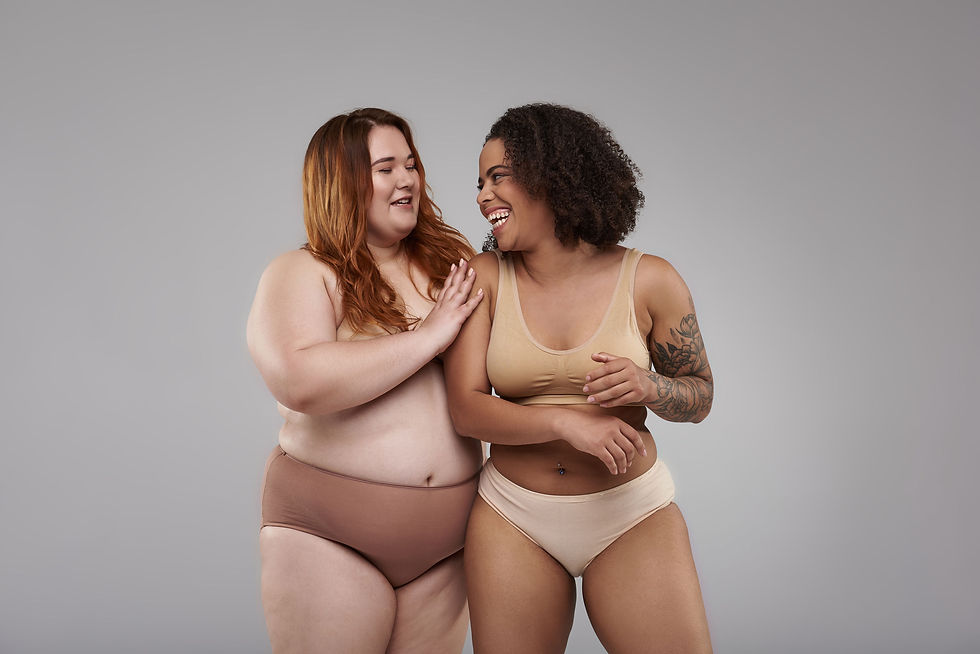 Two plus size women in underwear laughing and looking at each other