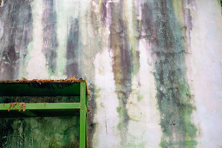 Kleurpatronen gevormd door sijpelend vocht, schimmel en tijd in een verlaten gebouw.