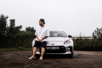 Front end of the Toyota GR86 in Singapore with David Foo, Founder of Road Pilgrim, sitting on the bonnet