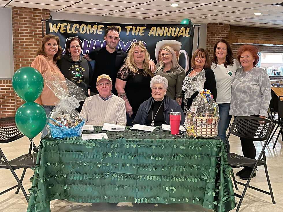 A large group of people smiling behind the sign in table at the event.