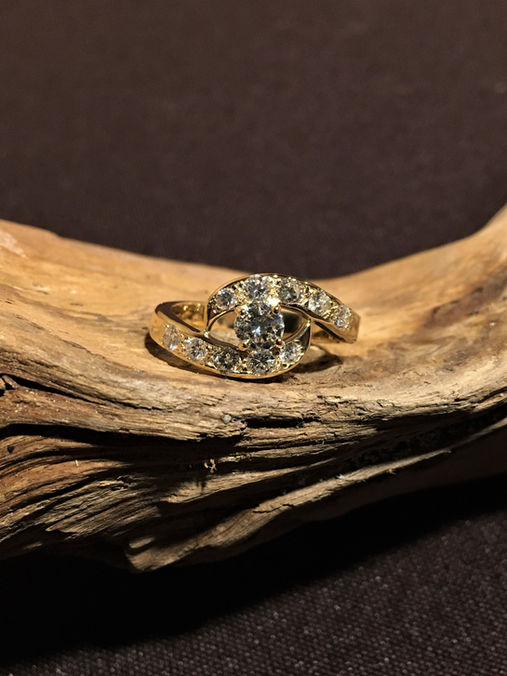 Un solitaire accompagné en or jaune orné d’une pierre centrale maintenue par 4 griffes afin d’en souligner son éclat et entouré par deux vagues recouverte de diamants par un discret serti grain