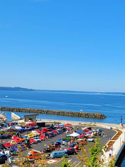 Waterland Wheels car show at Des Moines Marina, featuring classic and modern cars with polished chrome, powerful engines, detailed dashboards, and scenic views of the Puget Sound, complemented by live music, food trucks, and a beer garden