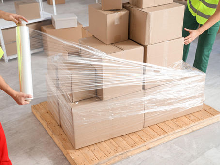 Warehouse workers wrapping boxes using stretch film