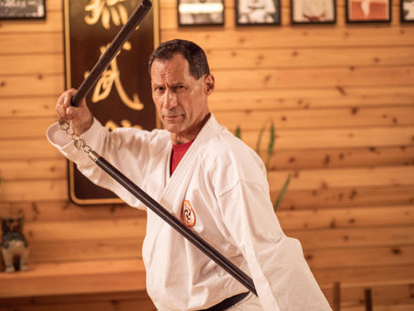 Pedro Bernardy practicing a martial arts technique with a staff in his dojo.