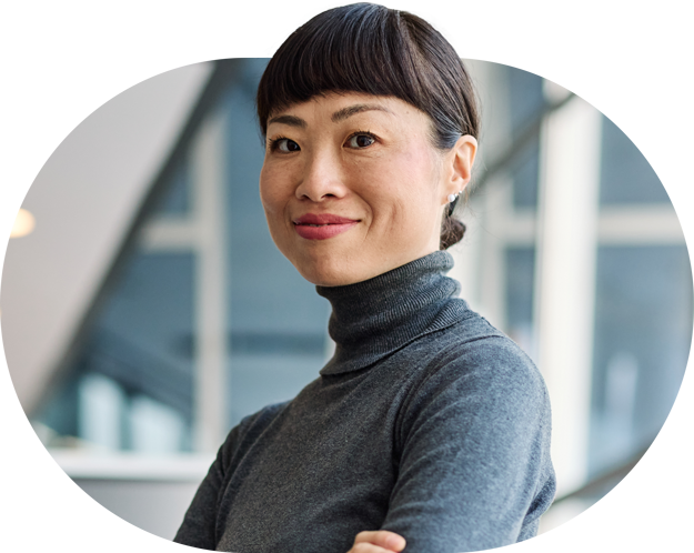 An Asian lady smiling casually at the camera with her arms crossed