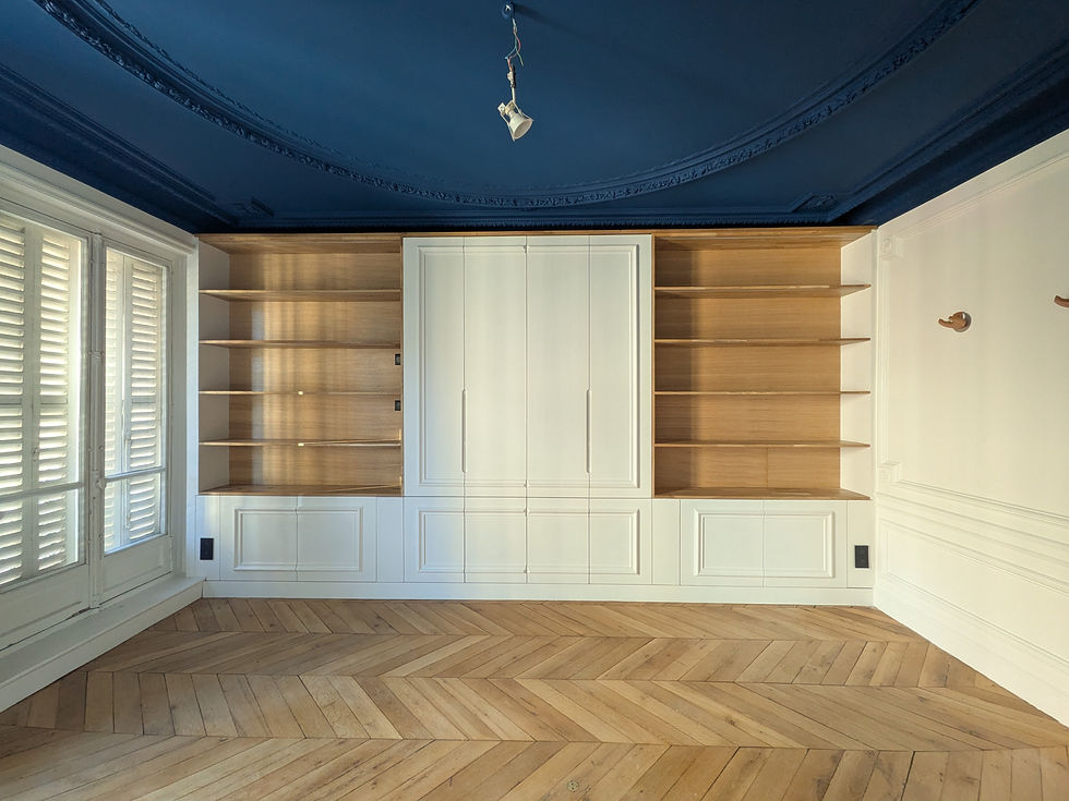 Pièce vide élégante avec rangements encastrés blancs et bois, plafond bleu nuit, parquet en chevrons et fenêtres à volets.