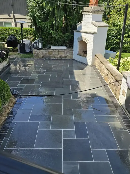 Stone patio with outdoor fireplace and grill.