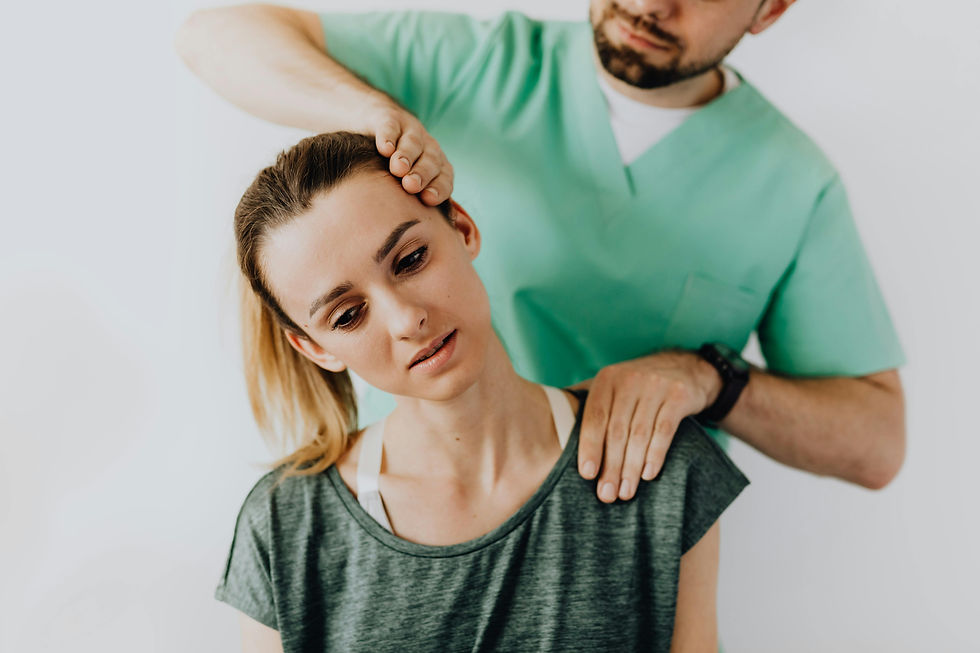 A therapist in a green uniform assists a woman in a gray shirt with neck therapy. She looks relaxed in a bright, minimal setting.
