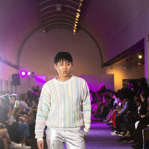 A light toned man with brown hair on a fashion show runway