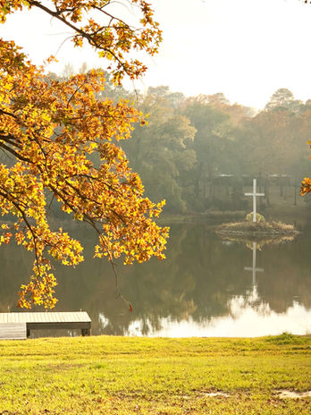 Lake in fall with orange foliage and cross island in distance.