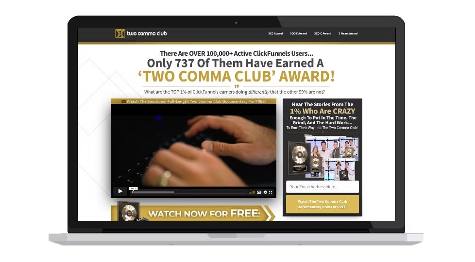 Laptop screen showing a webpage about the "Two Comma Club Award" by ClickFunnels. Features a video with hands typing and a signup section.