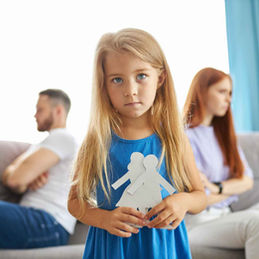 Young girl holding paper couple, with separated parents; Family Law.