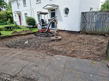 Mini digger preparing ground for driveway installation near house