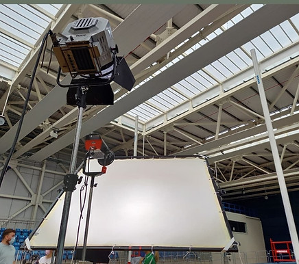 Large lighting kit shines bright inside the building, with people in view.