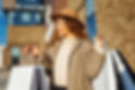 Woman wearing hat and coat, holding shopping bags, smiling outside, Omni Shopping Centre.