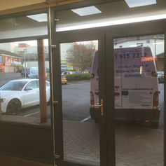 Glass doors leading to a parking area with a white van