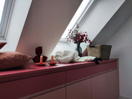 Pink built-in window seat with candles, blanket, and dried flowers