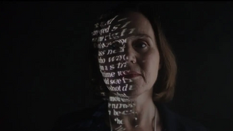 Woman with text projected on face in front of a black background