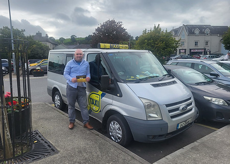 Man stands next to a taxi with visible text and logo outside.
