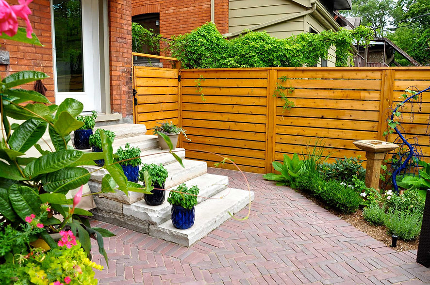 Stone steps, potted herbs, wooden fence, and brick patio