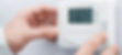 Hands adjusting a white thermostat on a wall, displaying 24.5°C and time 14:44. The background is plain white, creating a calm setting.