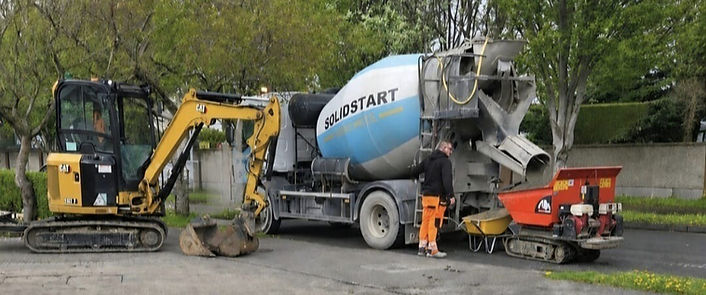 SolidStart concrete truck, mini excavator, and worker at a site