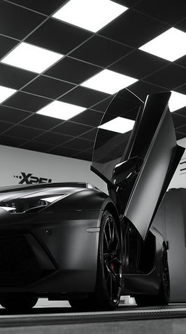 Black Lamborghini Aventador with doors open in showroom