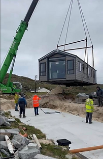 Crane lifting mobile home onto foundation