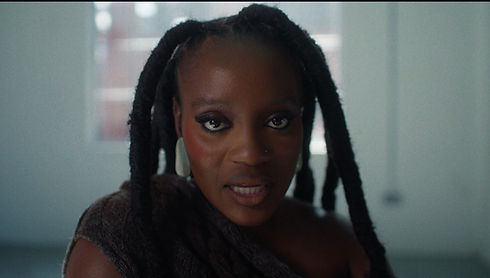 Close-up of a woman with dark hair and makeup, looking directly at camera.