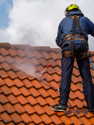 Worker pressure washing a tiled roof