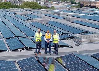 Three workers standing on a roof with solar panels