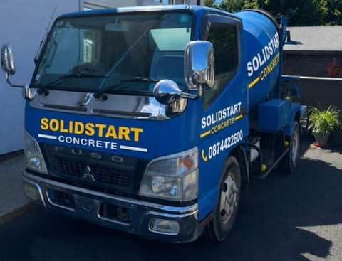Blue Solidstart Concrete Fuso mixer truck parked outside.