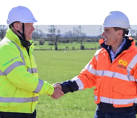 Two engineers shaking hands in a field