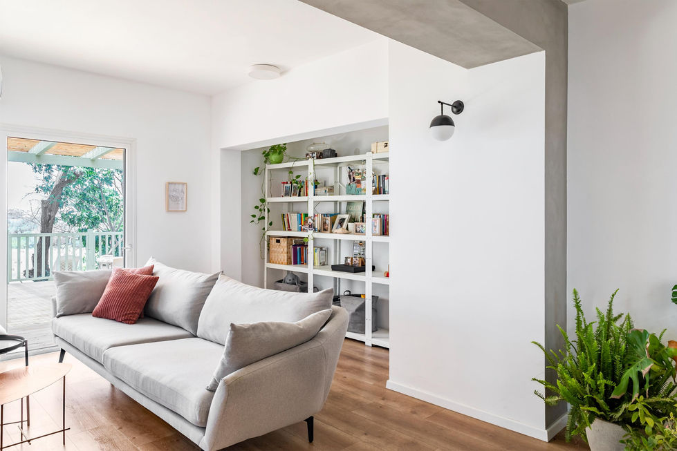 סלון מואר עם ספה לבנה וקיר ספרים מובנה