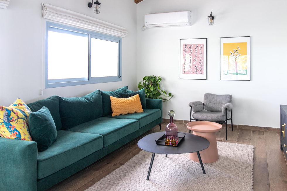 סלון עם ספה ירוקה, שולחן עגול ותמונות על הקיר