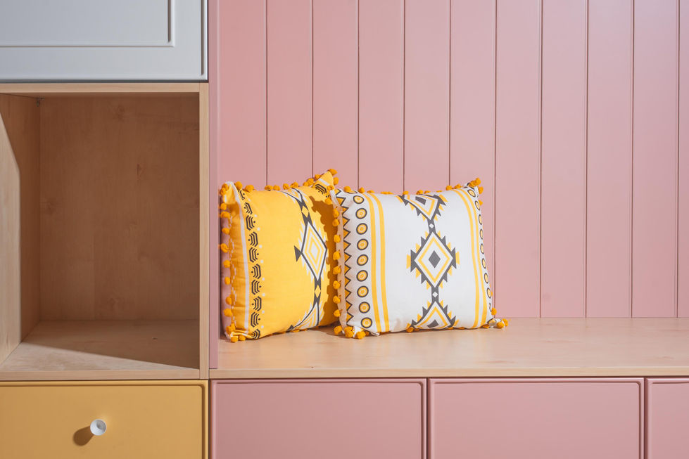 ספסל נגרות עם כריות צבעוניות על רקע קיר ורוד