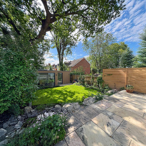 Organic natural garden in Raynes Park, South West London featuring tumbled mint sandstone paving, Kent ragstone boulders, wildlife pond, bespoke fencing, and garden room – Luxury Gardens.