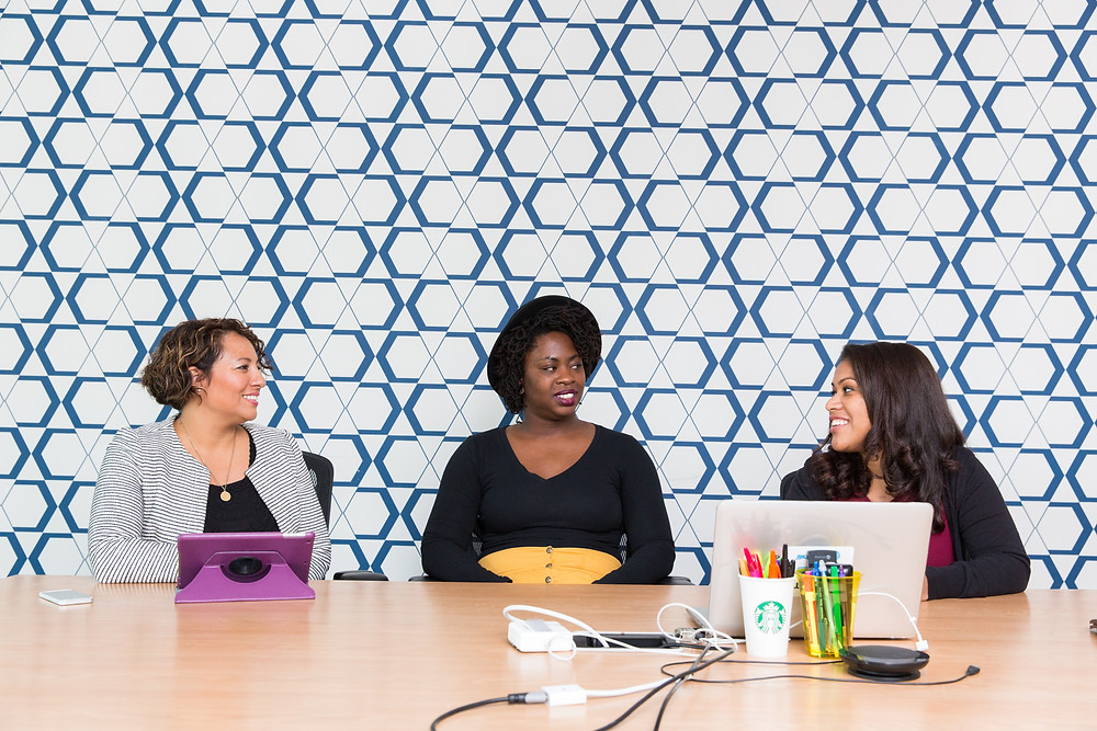 Three women smiling at an office desk