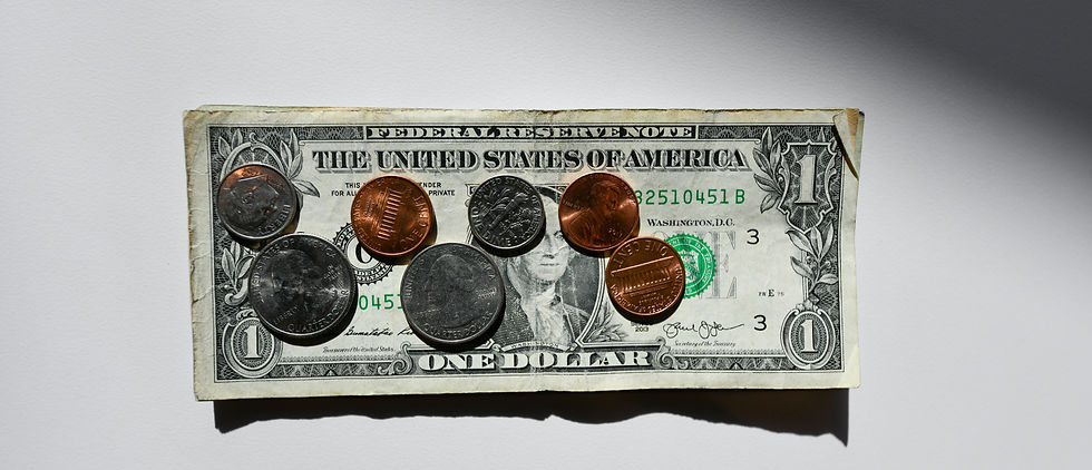 A dollar bill with various coins on top, including quarters, dimes, and pennies. White background with shadow. Crisp, close-up view.