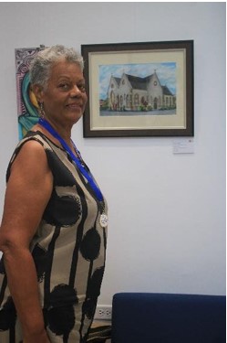 An artist poses proudly beside her artwork