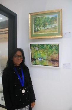 An artist poses proudly beside her artwork