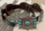Close-up of a brown leather belt with large turquoise stone accents.