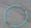 Turquoise beaded ankle bracelet displayed on slate background, jewelry fashion accessory.