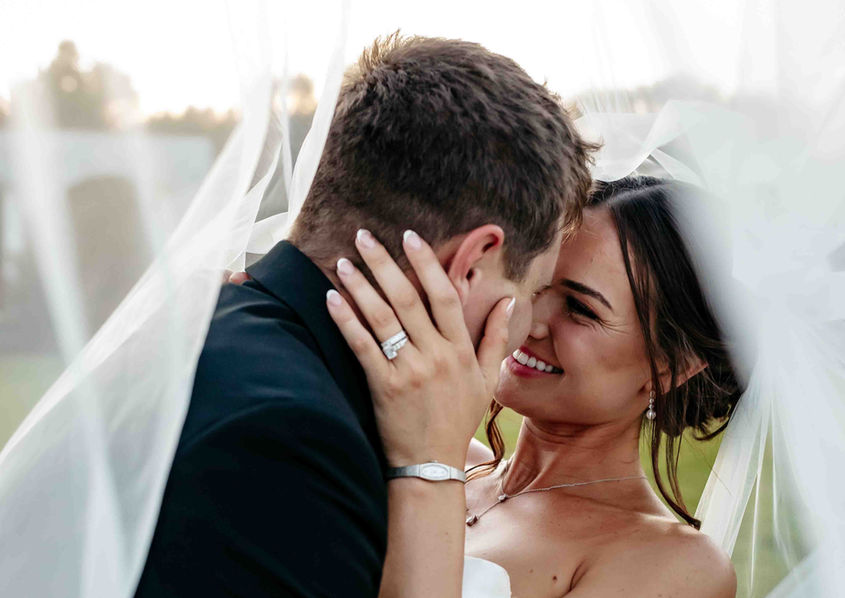 Bride laughing at groom under veil
