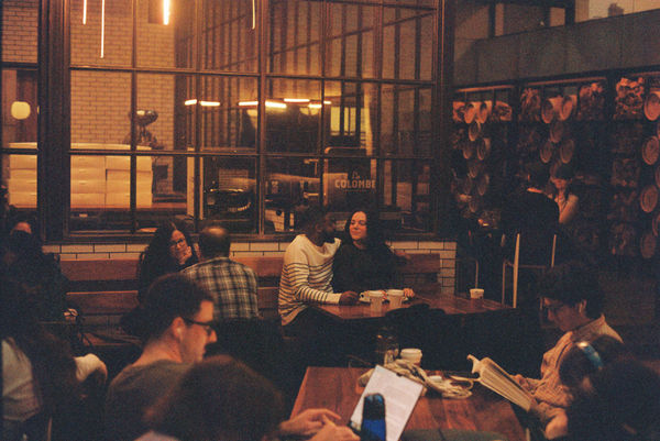 Couple looking at each other in a coffee shop amongst guests