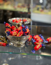 Red chocolatecaramels called dumle are in an antique silver bowl in a glass case