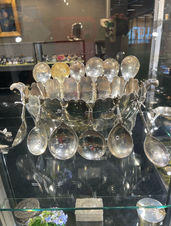antique silver spoons with a larger spoon surface and oblong narrower handles with different shapes resting against a silver bowl