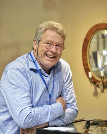 Jan Ribbhagen med stort leende i en ljusblå skjorta lutad över en glasdisk